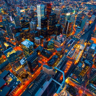 Aerial view of downtown Toronto at dusk, with the Financial District’s towers, Fairmont Royal York, Union Station’s rail platforms, and the illuminated Gardiner Expressway.