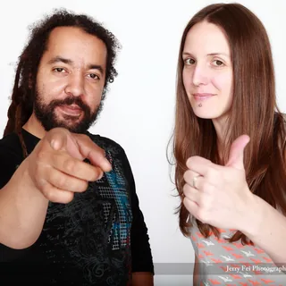 Lisa Kruchak and Dave Matthews posing against a white background, with the man pointing toward the camera and the woman giving a thumbs-up.
